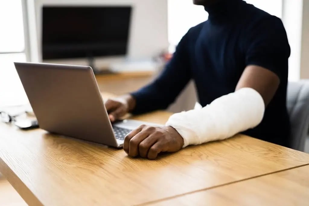 Man with Injured Arm Working on Laptop