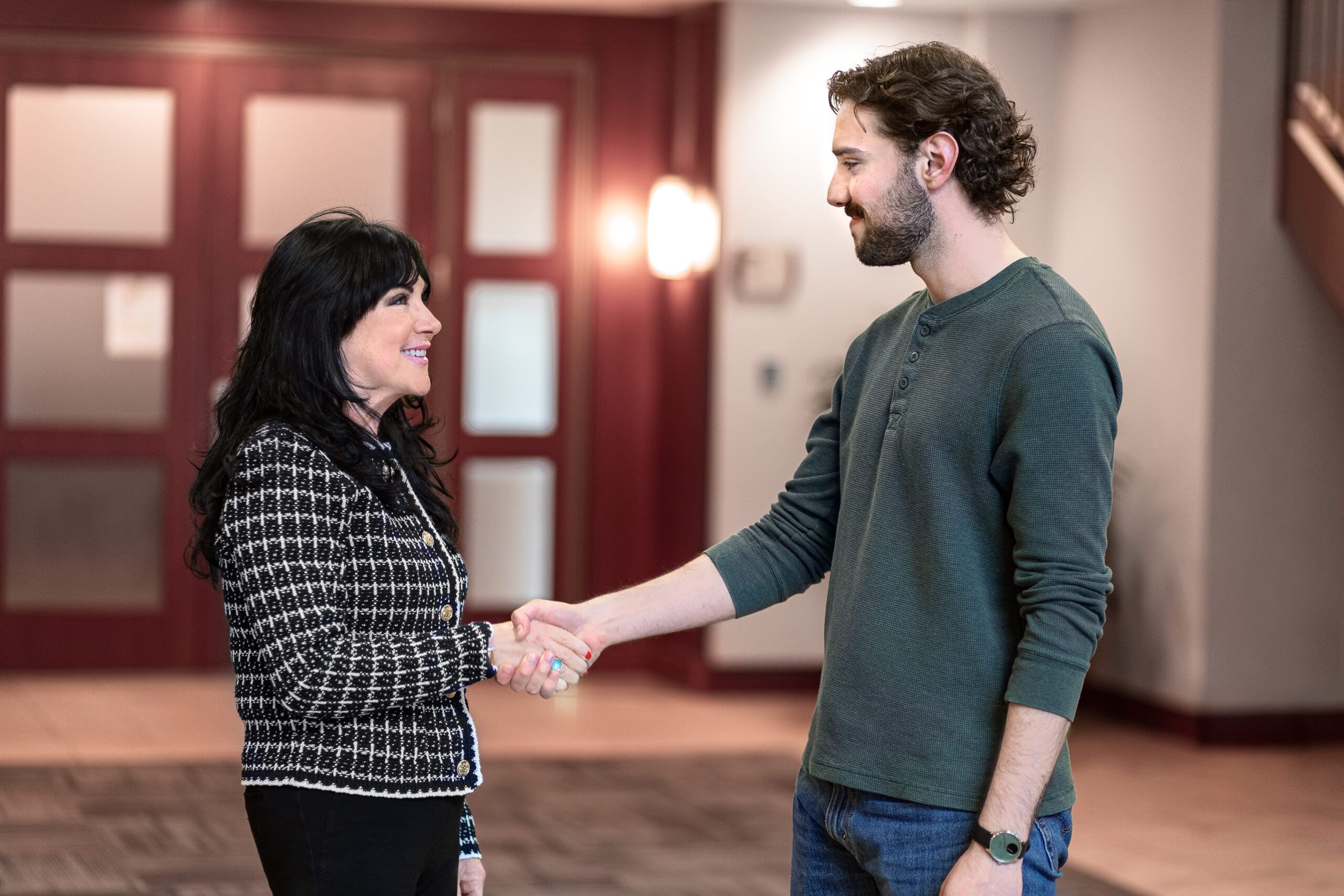 Two people in professional attire shaking hands in a business setting