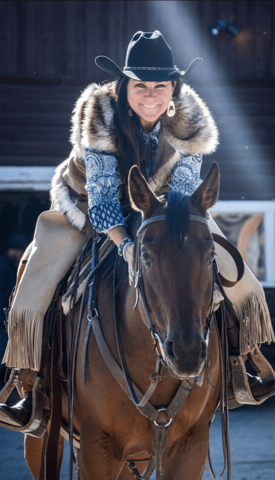 Paula Robinson horseback riding outdoors wearing a cowboy hat
