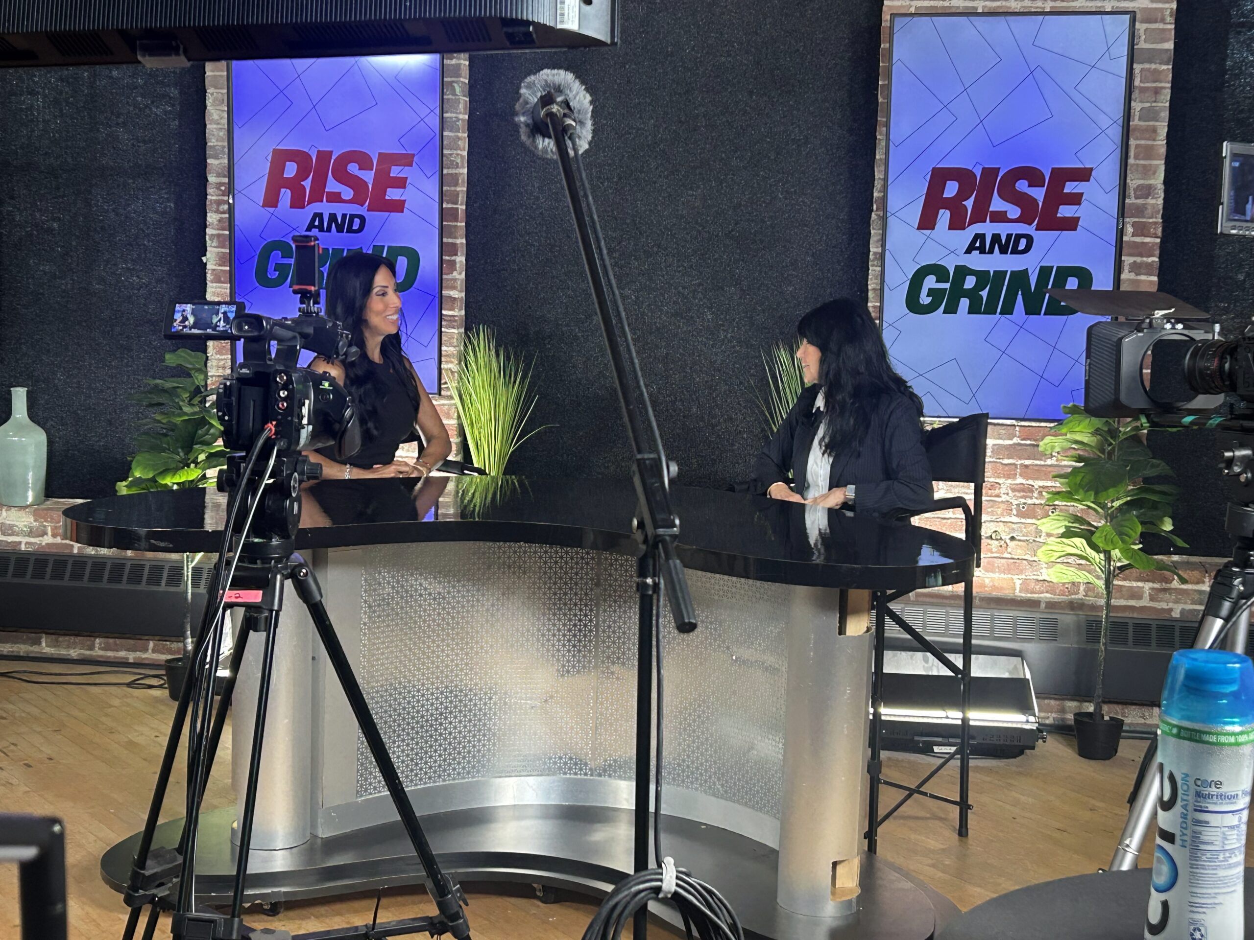 Professional TV interview set with studio lighting, desk, and backdrop for Rise and Grind program